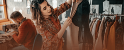Woman sewing fabric by hand, surrounded by tailoring tools in a creative workspace.